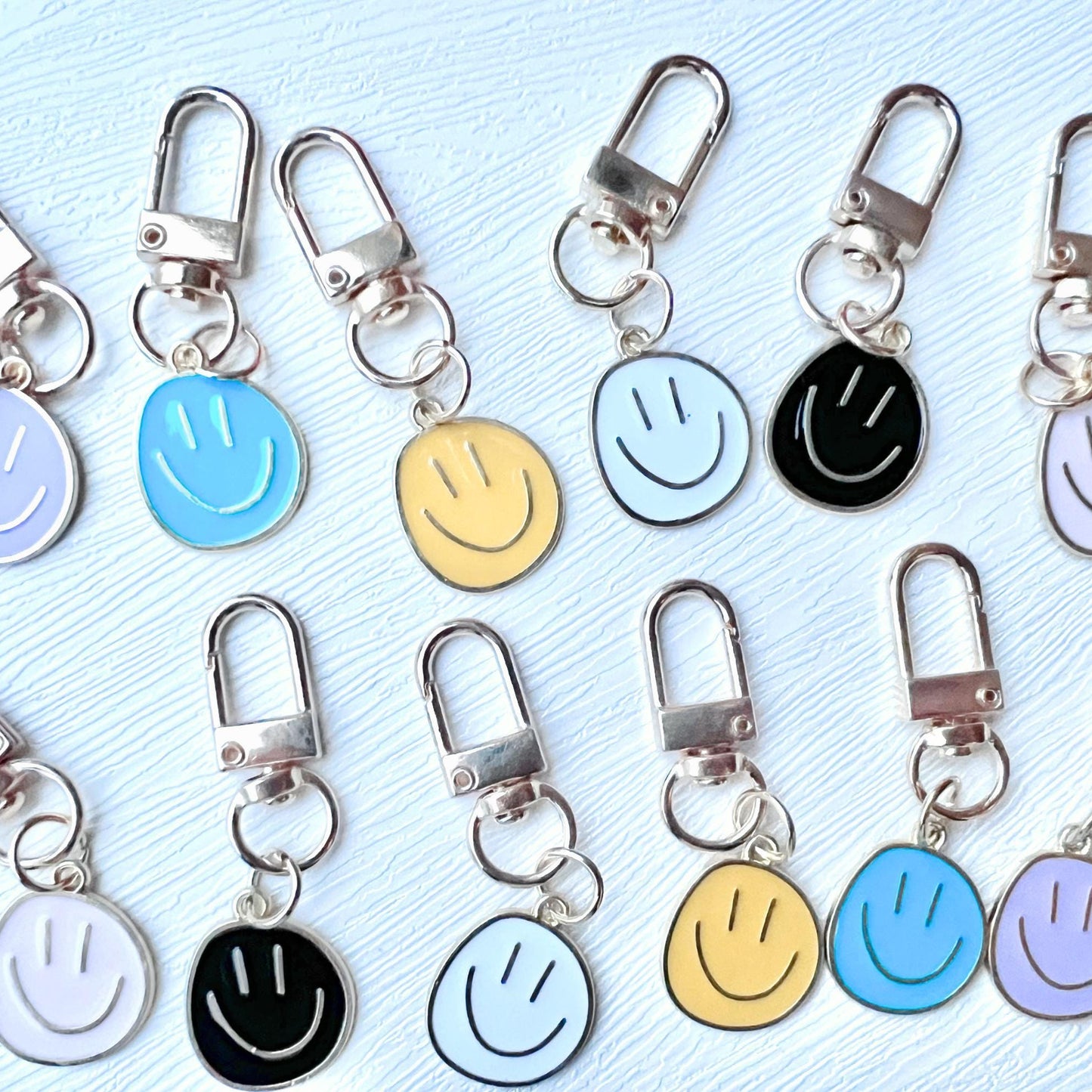 Set of smiley face keychains in various colors on a light blue background