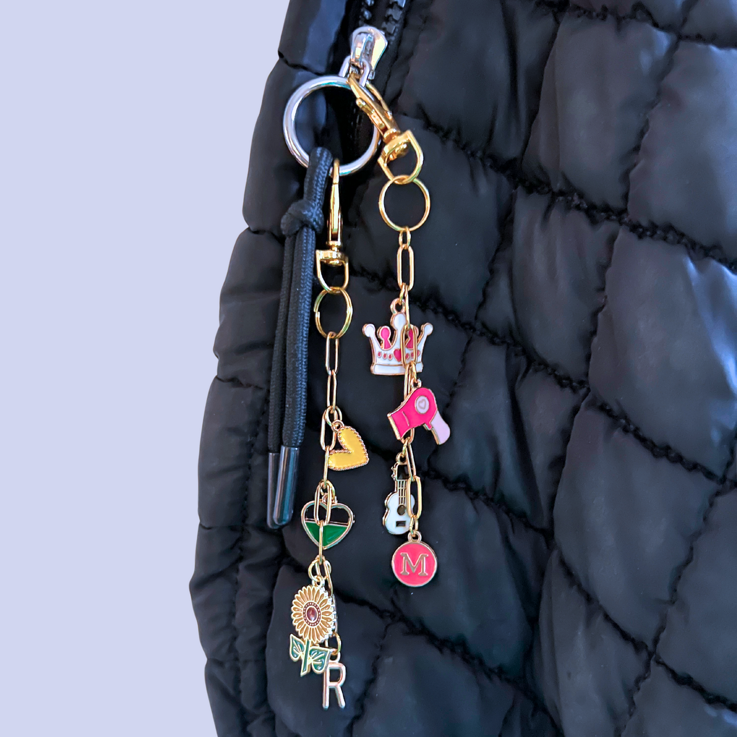 Keychain with various charms attached to a black quilted bag.