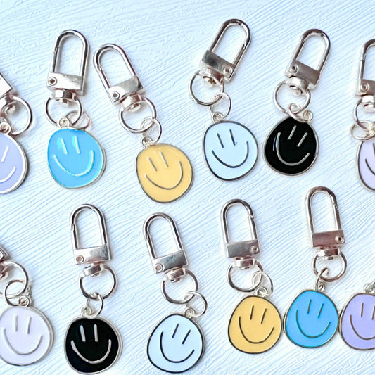 Set of smiley face keychains in various colors on a light blue background