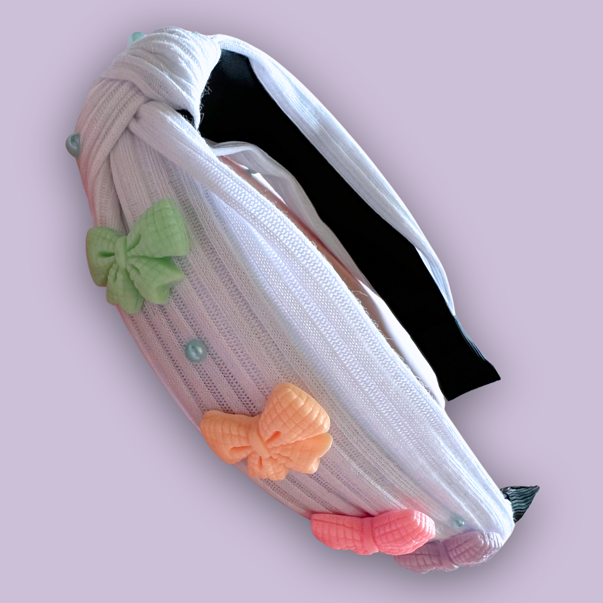 A white headband with colorful coquette bow charms and blue pearl rhinestones 