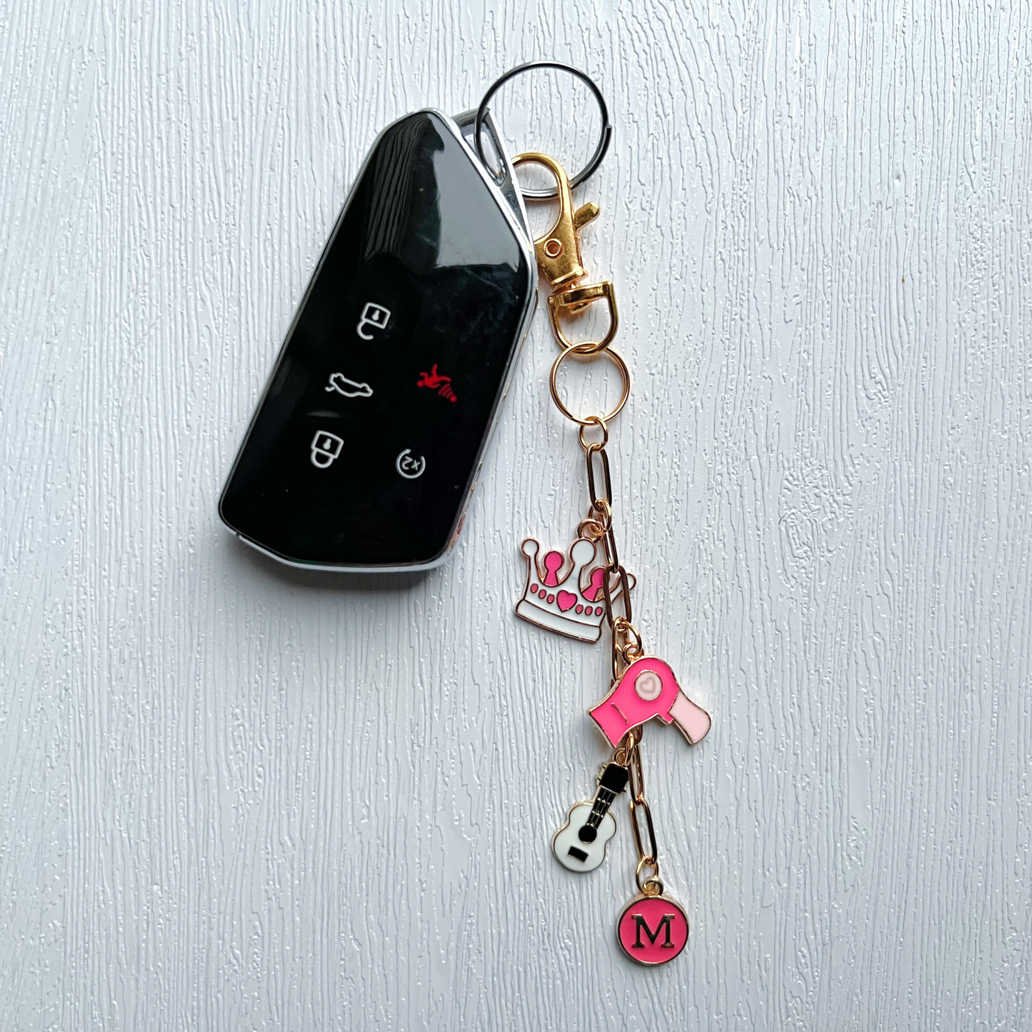 Keychain with charms attached to a car key on a light gray background