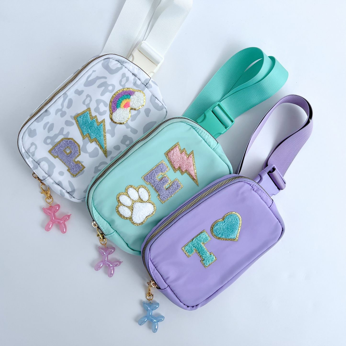 Three small bags in gray, teal, and purple with decorative elements on a light gray background