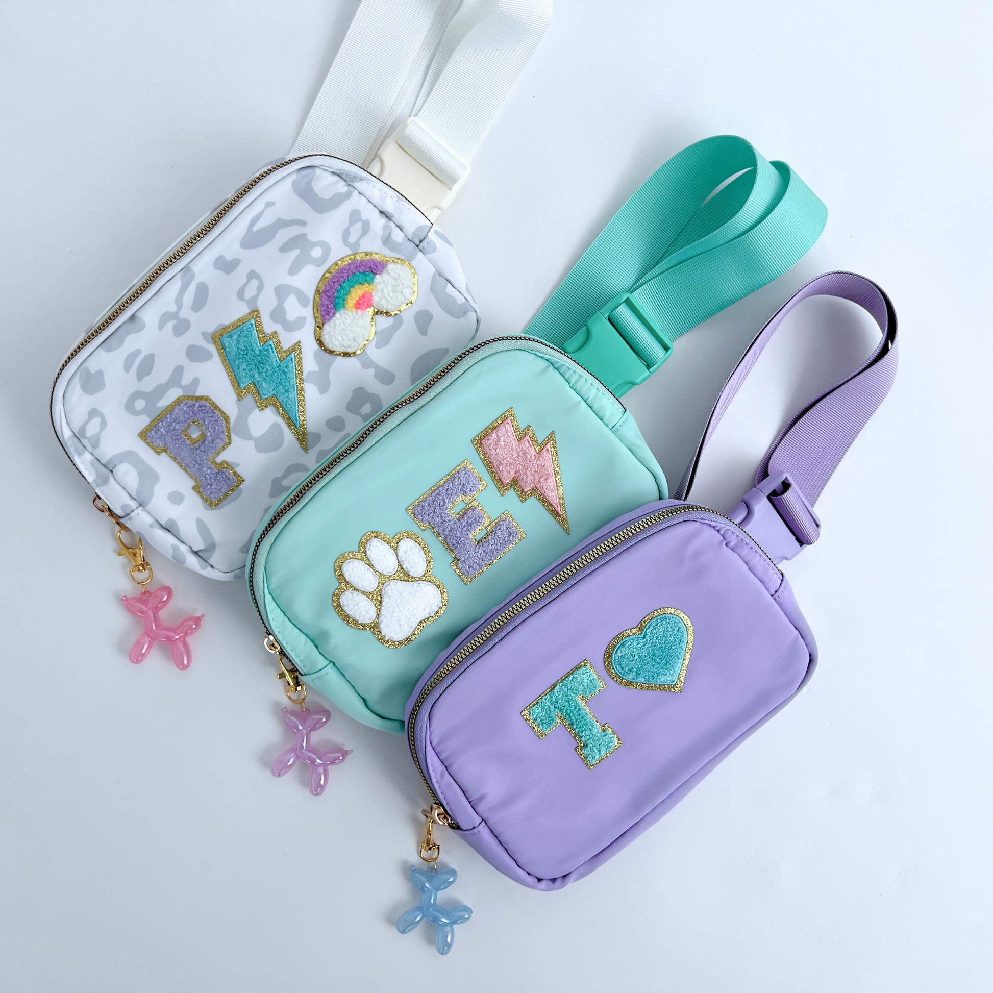 Three small bags in gray, teal, and purple with decorative elements on a light gray background