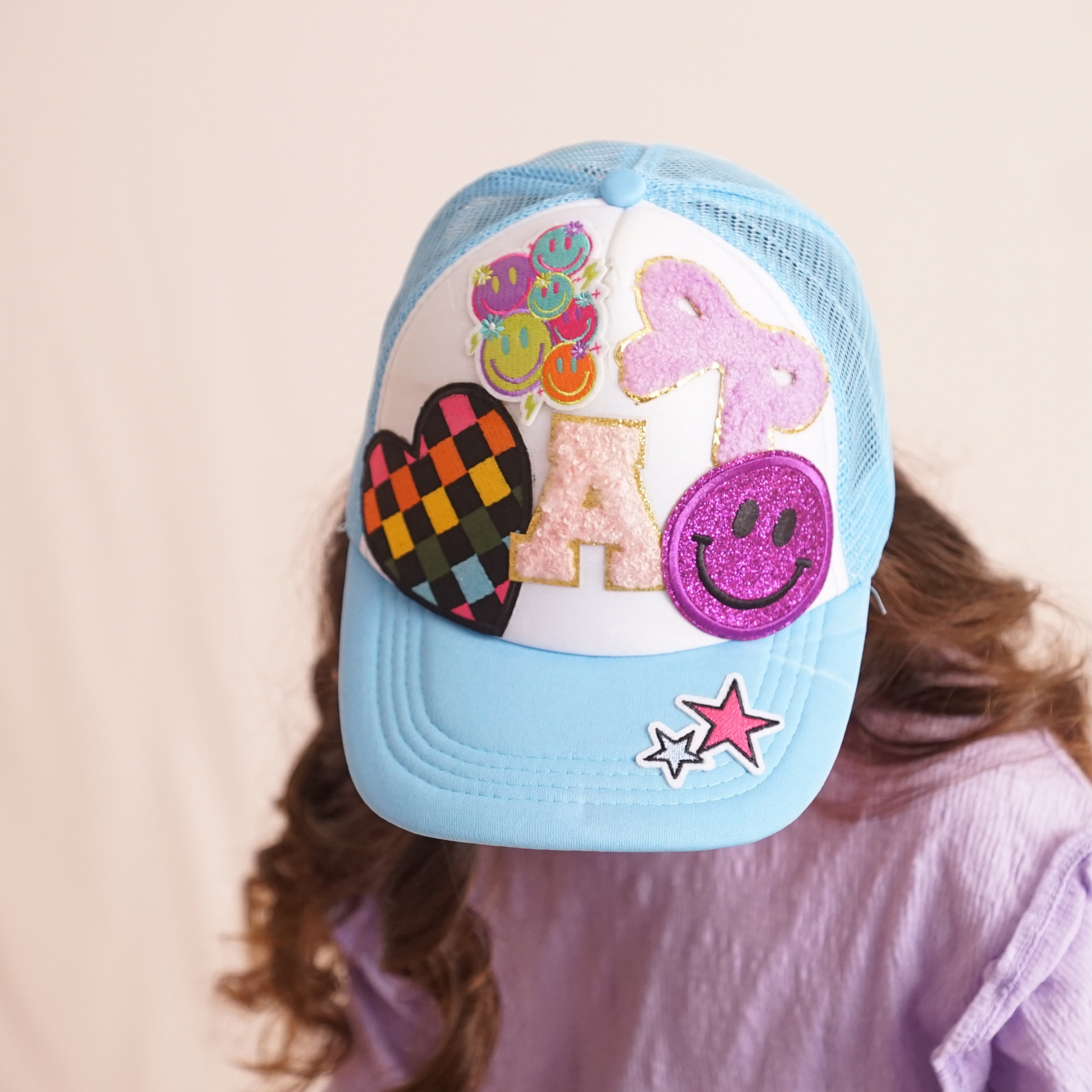 Light blue cap with colorful decorative patches on a beige background