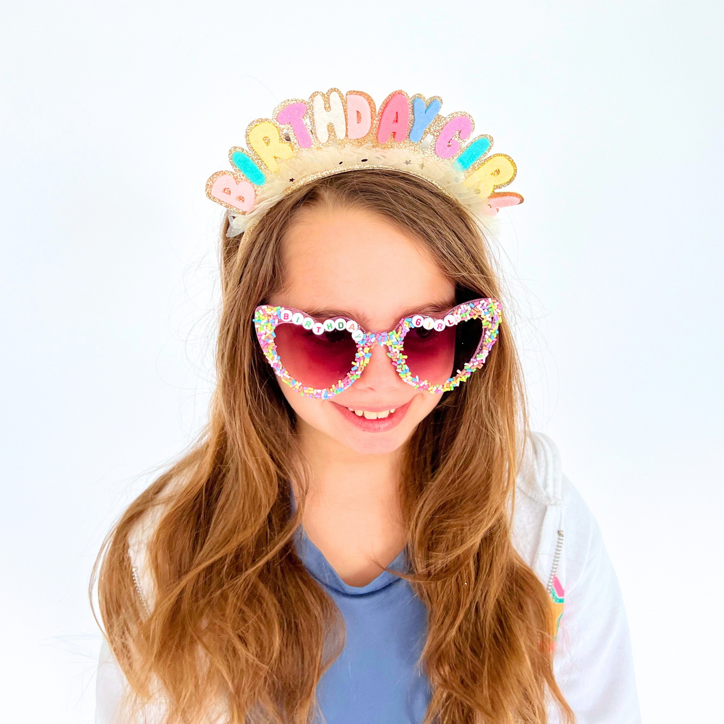 Girl wearing birthday headband and sprinkle glasses – Smiling child modeling the headband and sunglasses for birthday look.