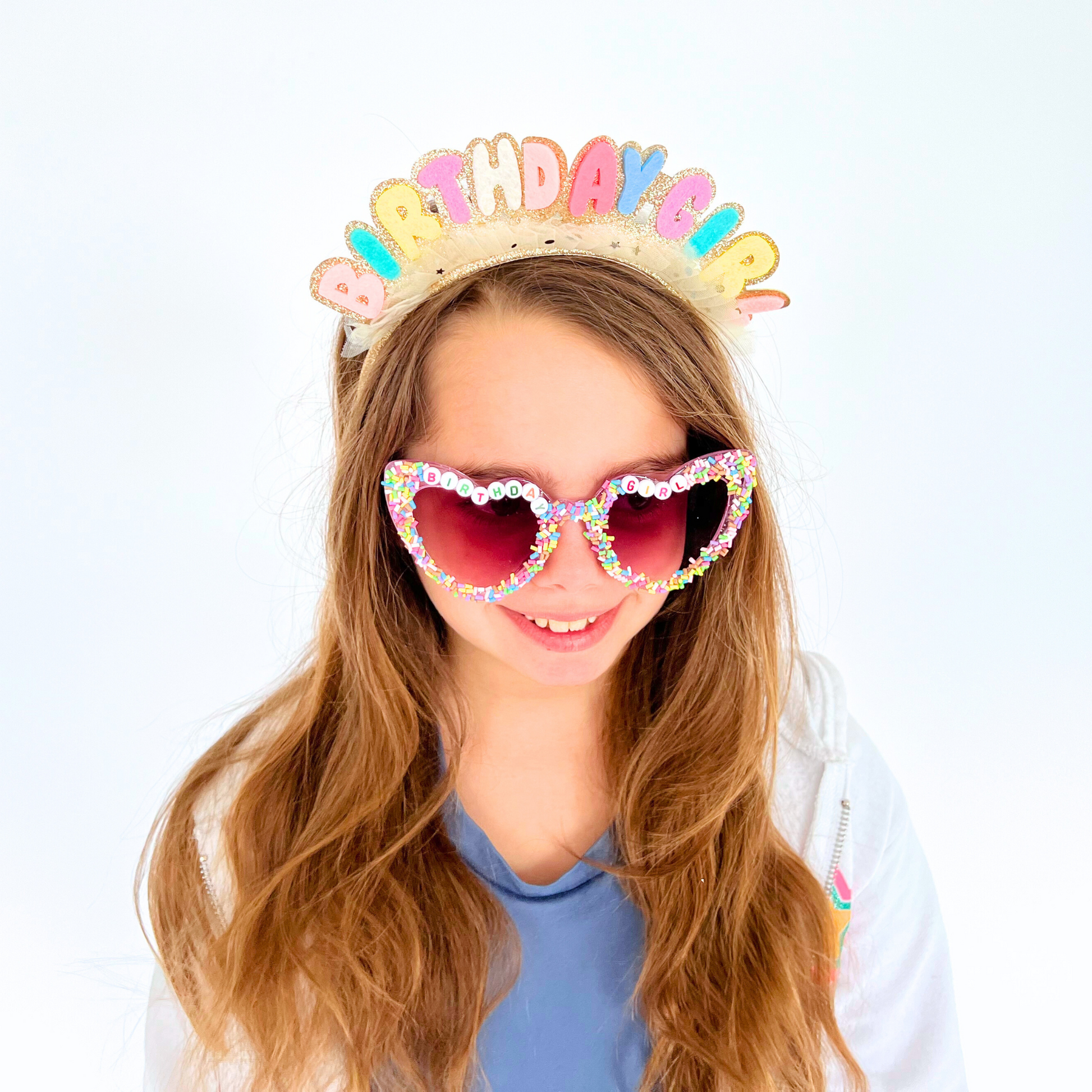 Girl wearing birthday headband and sprinkle glasses – Smiling child modeling the headband and sunglasses for birthday look.