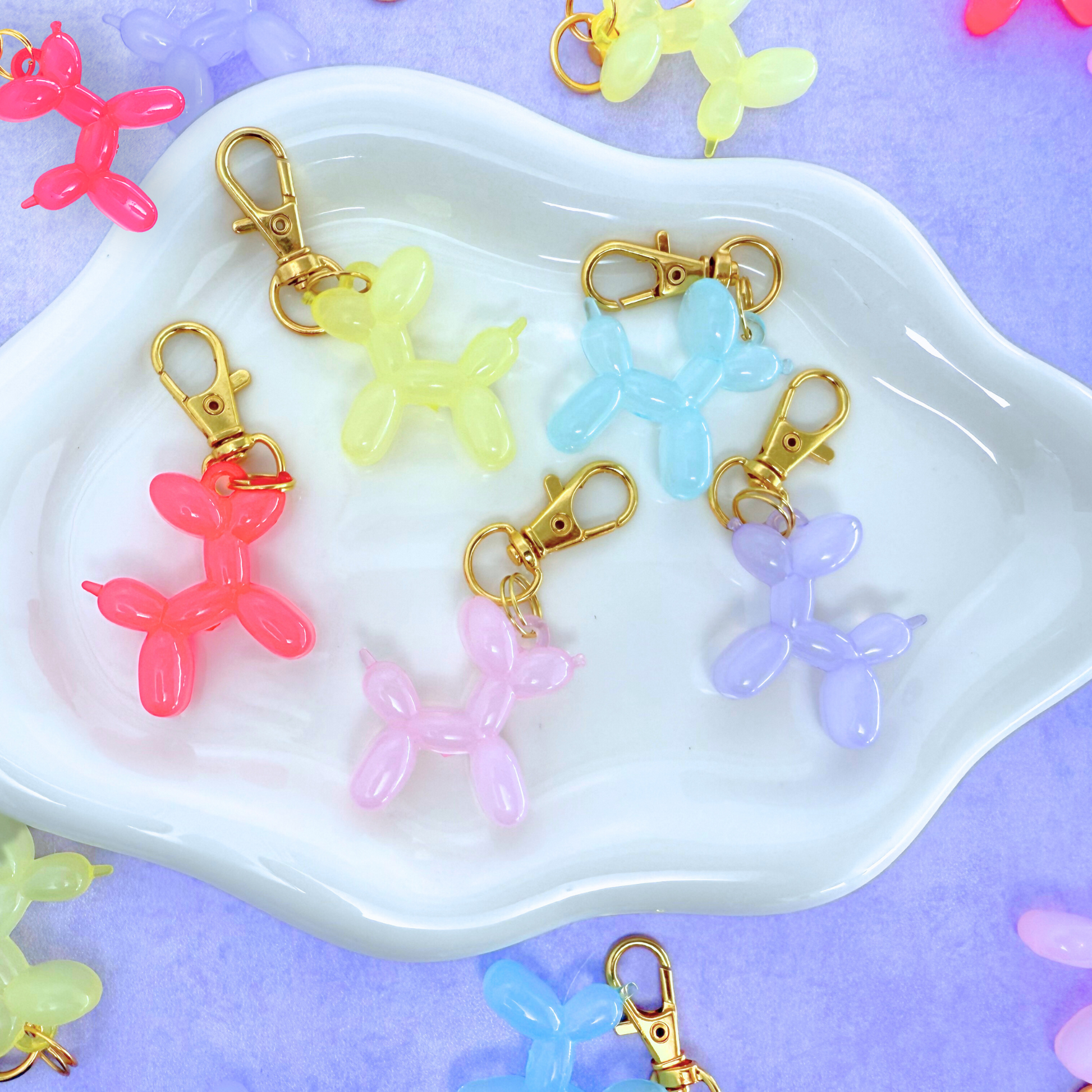 Colorful balloon dog keychains on a white dish with a purple background