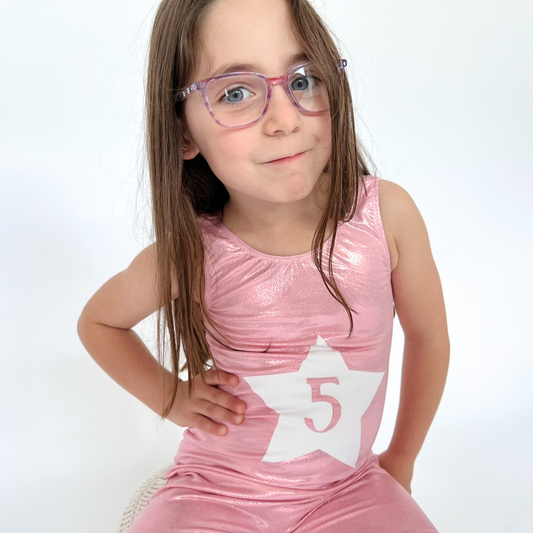 Young girl wearing a pink leotard with a star and number 5 on a white background
