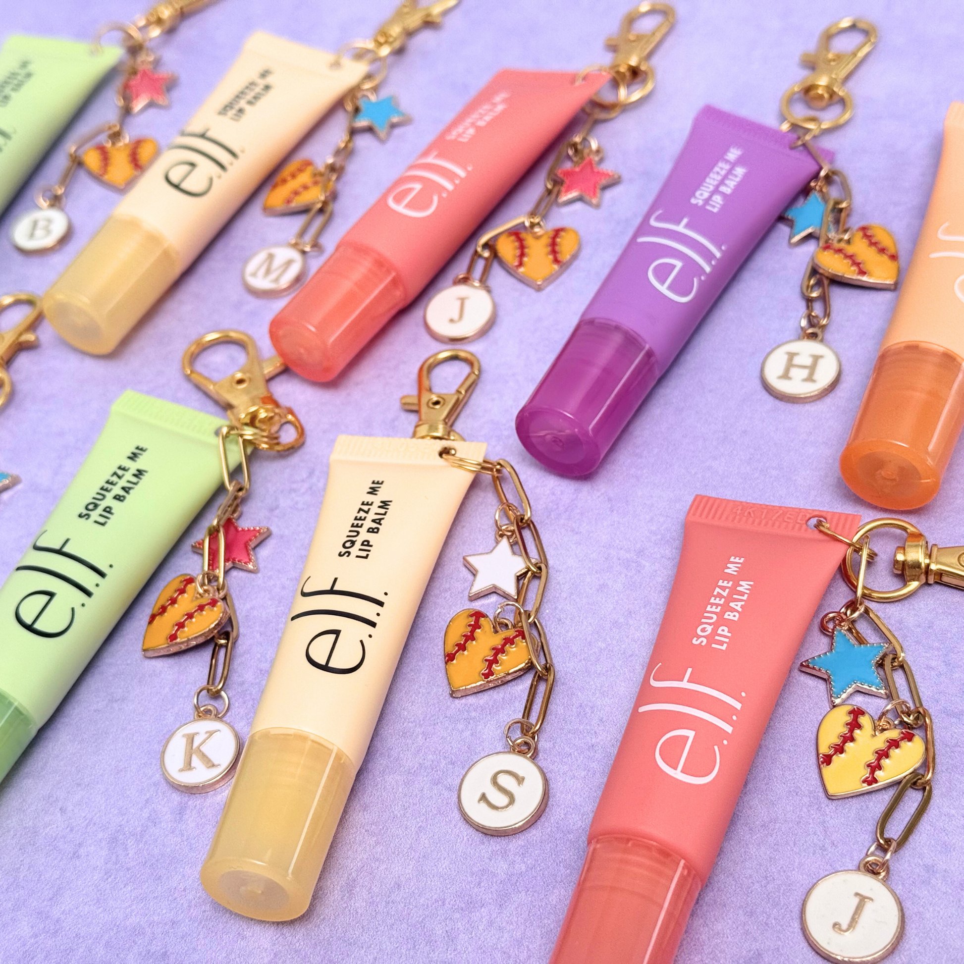 Collection of e.l.f. lip balm tubes with keychains on a purple background