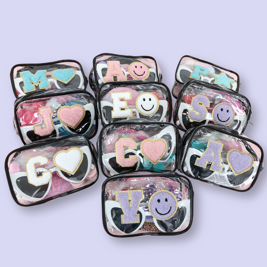 Group of personalized clear makeup bags arranged on lavender background, each featuring unique chenille patches and sunglasses.