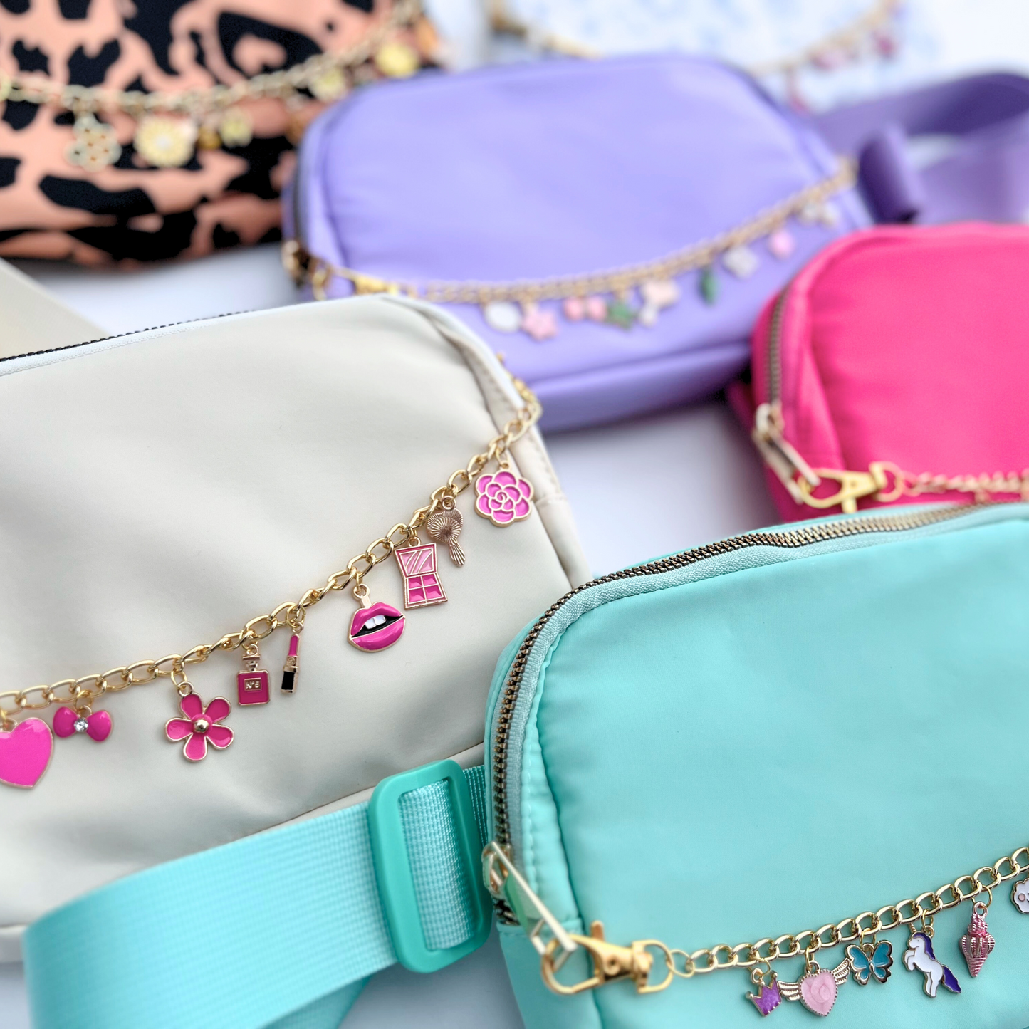 Colorful fanny packs with charm chains on a light background