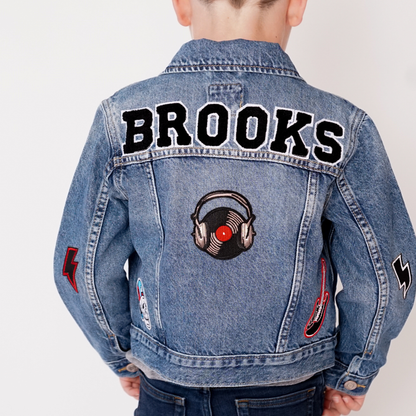 Denim jacket with 'Brooks' text and music-themed patches on a plain background