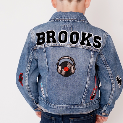 Denim jacket with 'Brooks' text and music-themed patch on a plain background