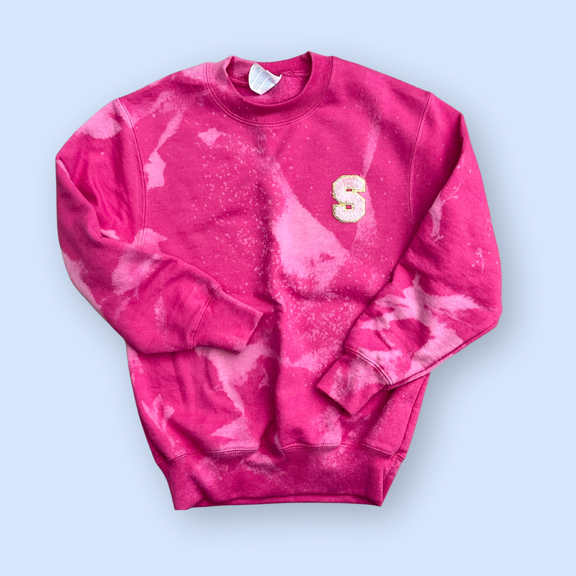 Pink tie-dye sweatshirt with a letter 'S' on a light blue background