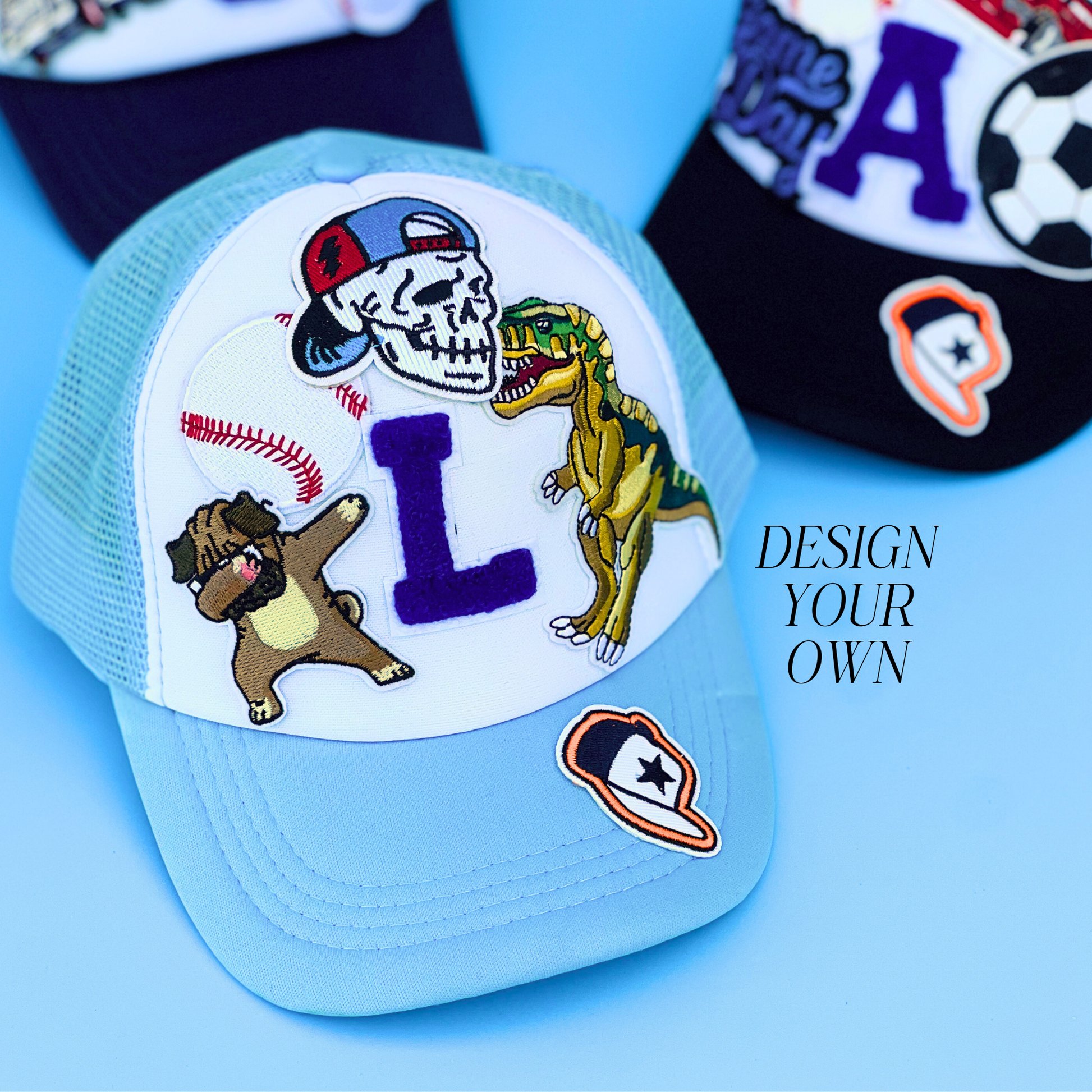 Light blue cap with various patches including a dinosaur, skull, and bear on a blue background.
