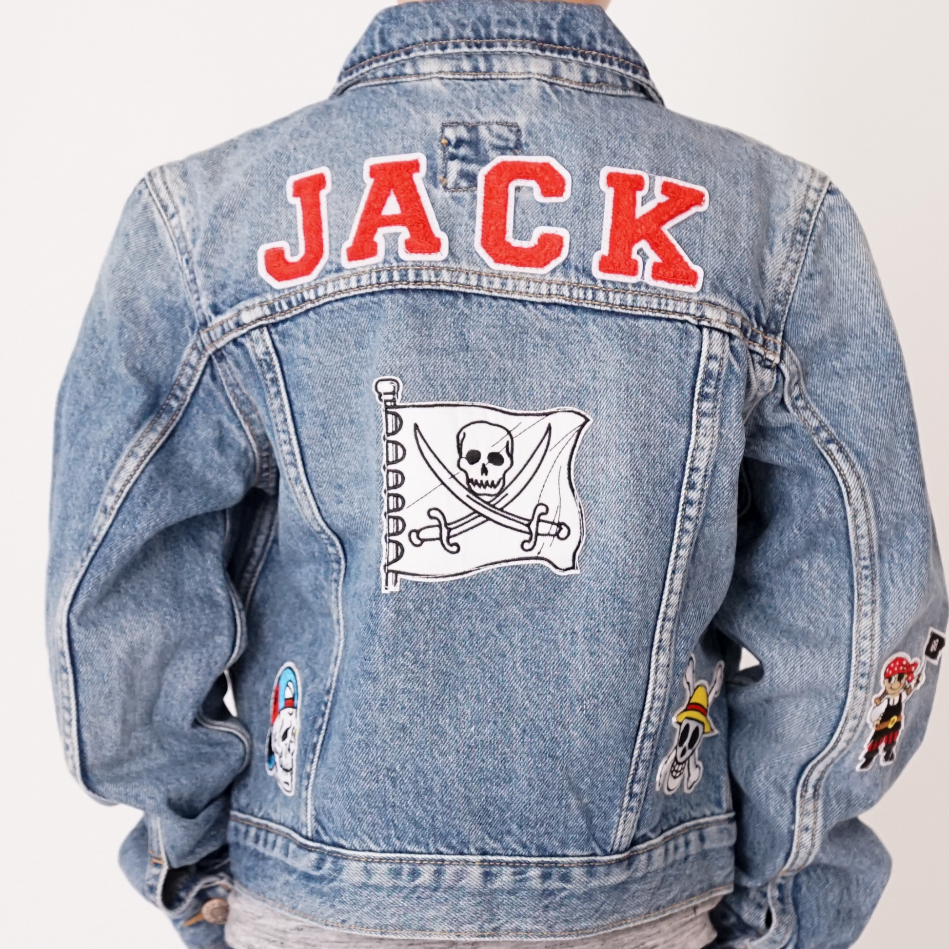 Denim jacket with 'JACK' text and skull flag patch on a white background