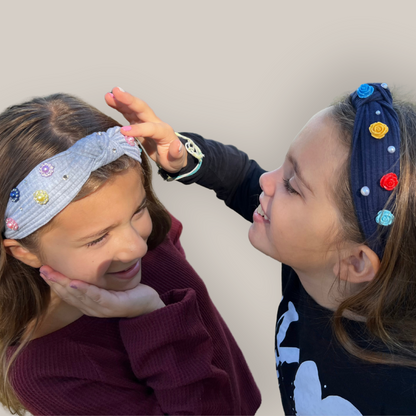 Two girls smiling while wearing charm headbands 