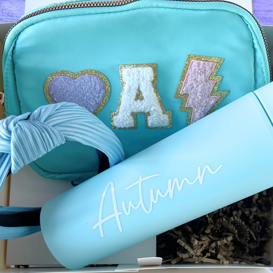Close-up of personalized fanny pack, headband, and tumbler in teal with “A” chenille patch and “Autumn” on the tumbler