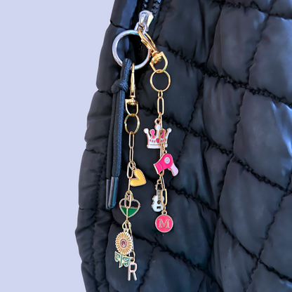 Keychain with various charms attached to a black quilted bag.