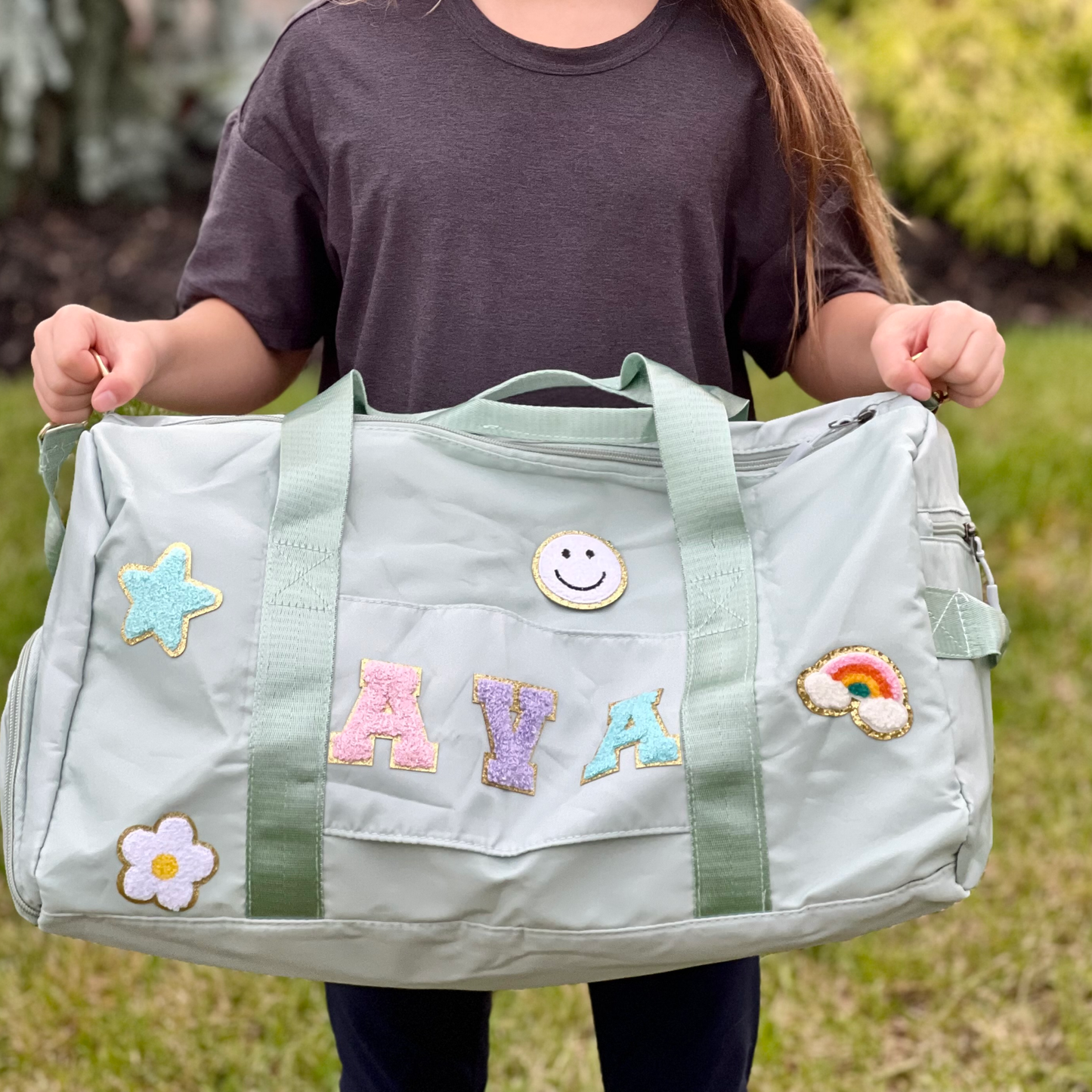 Child holding light green bag with AVA and happy face and soccer patches.