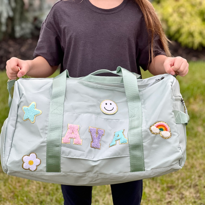 Child holding light green bag with AVA and happy face and soccer patches.