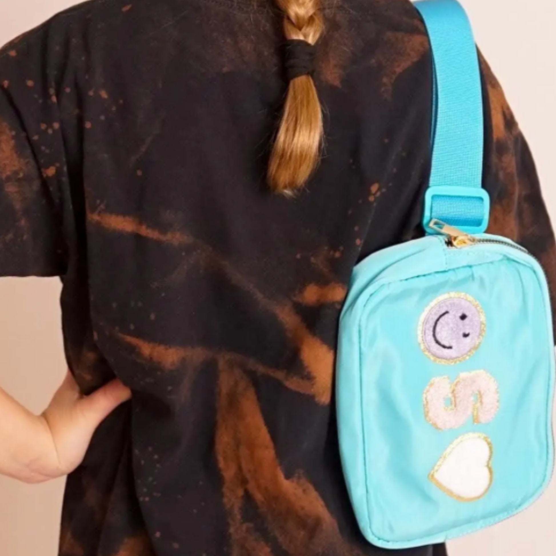 Close-up of girl wearing black shirt and S patch bag over the shoulder