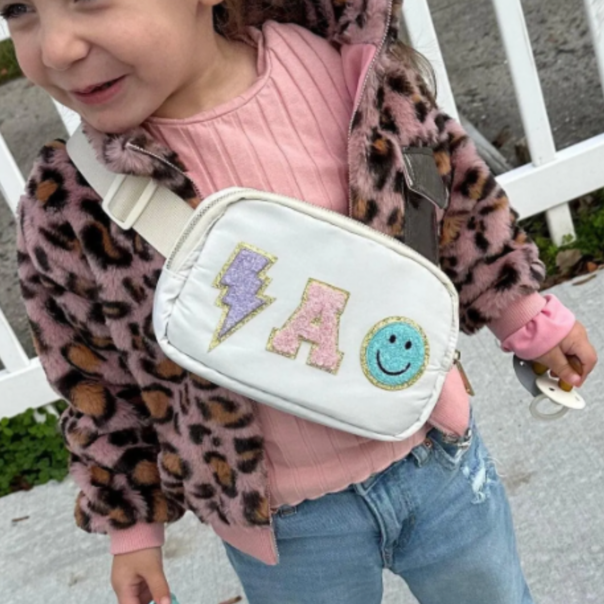 Girl wearing white fanny pack with A patch lightning patch and happy face patch
