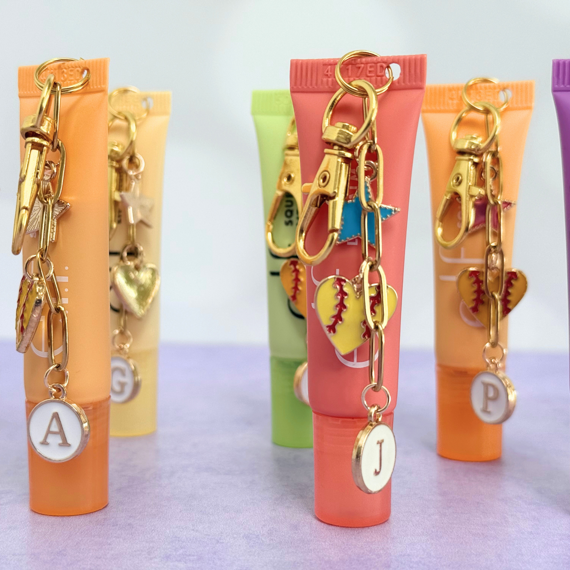 Colorful lip balm tubes with keychains and charms on a light gray background