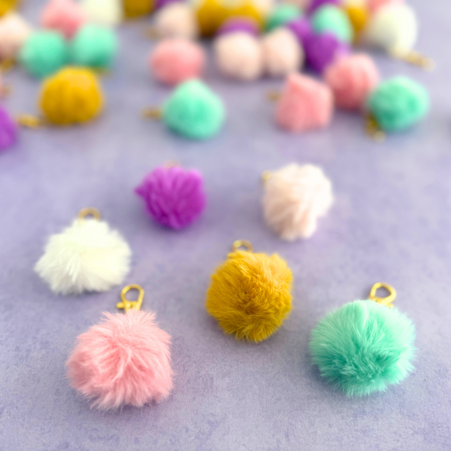 Colorful pom-pom keychains on a light purple background
