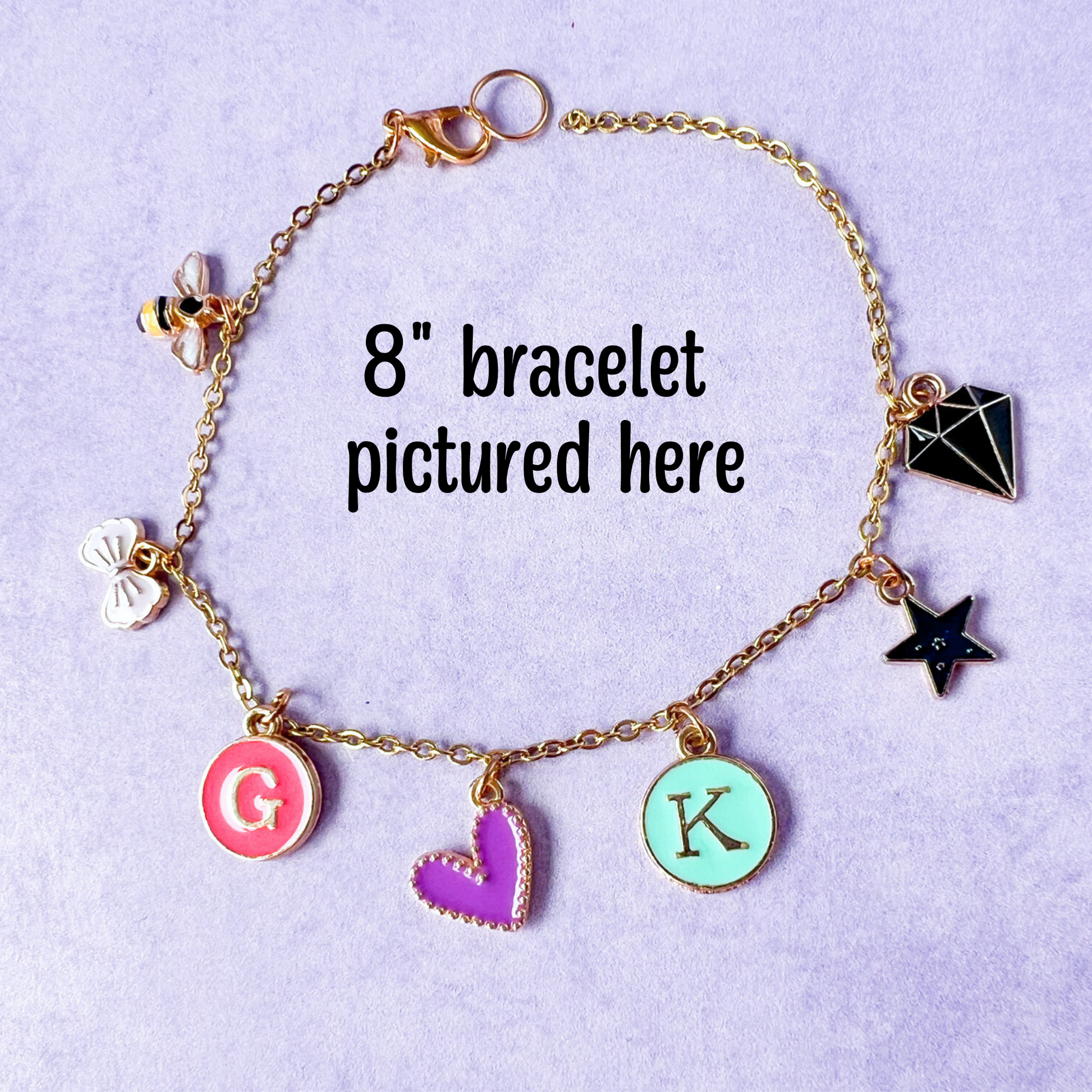 Gold bracelet with various charms on a light purple background