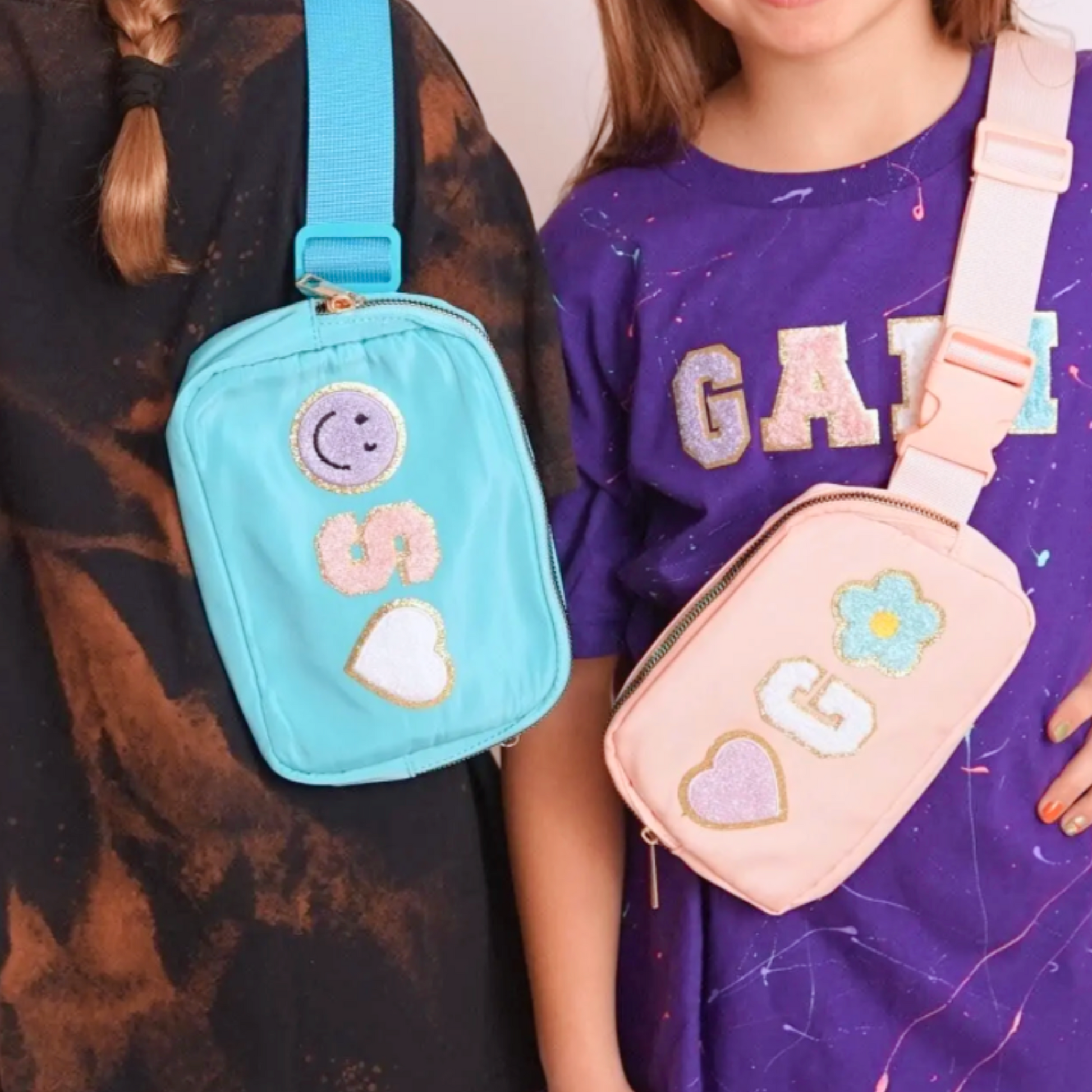 Girls in Tie dye shirts with blue and pink crossbody fanny packs with chenille letter patches