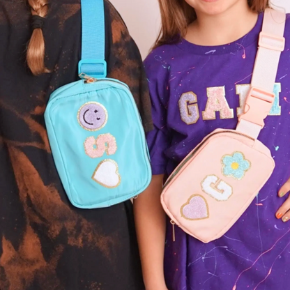Girls in Tie dye shirts with blue and pink crossbody fanny packs with chenille letter patches