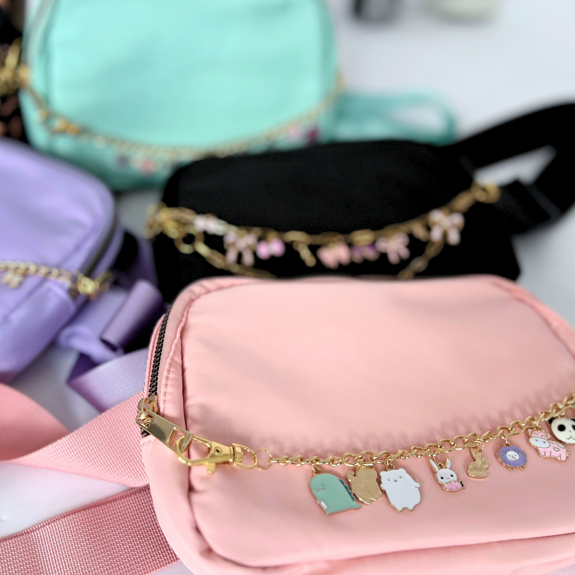 Gold bracelet with charms on a pink pouch with blurred colorful background