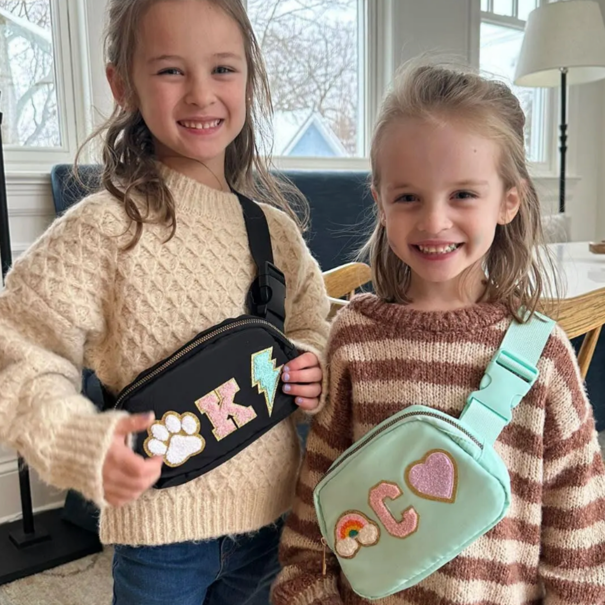 Two girls holding personalized fanny packs with names