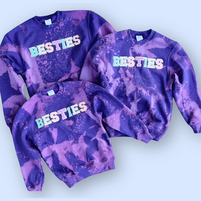 Three purple tie-dye sweatshirts with 'BESTIES' text on a white background