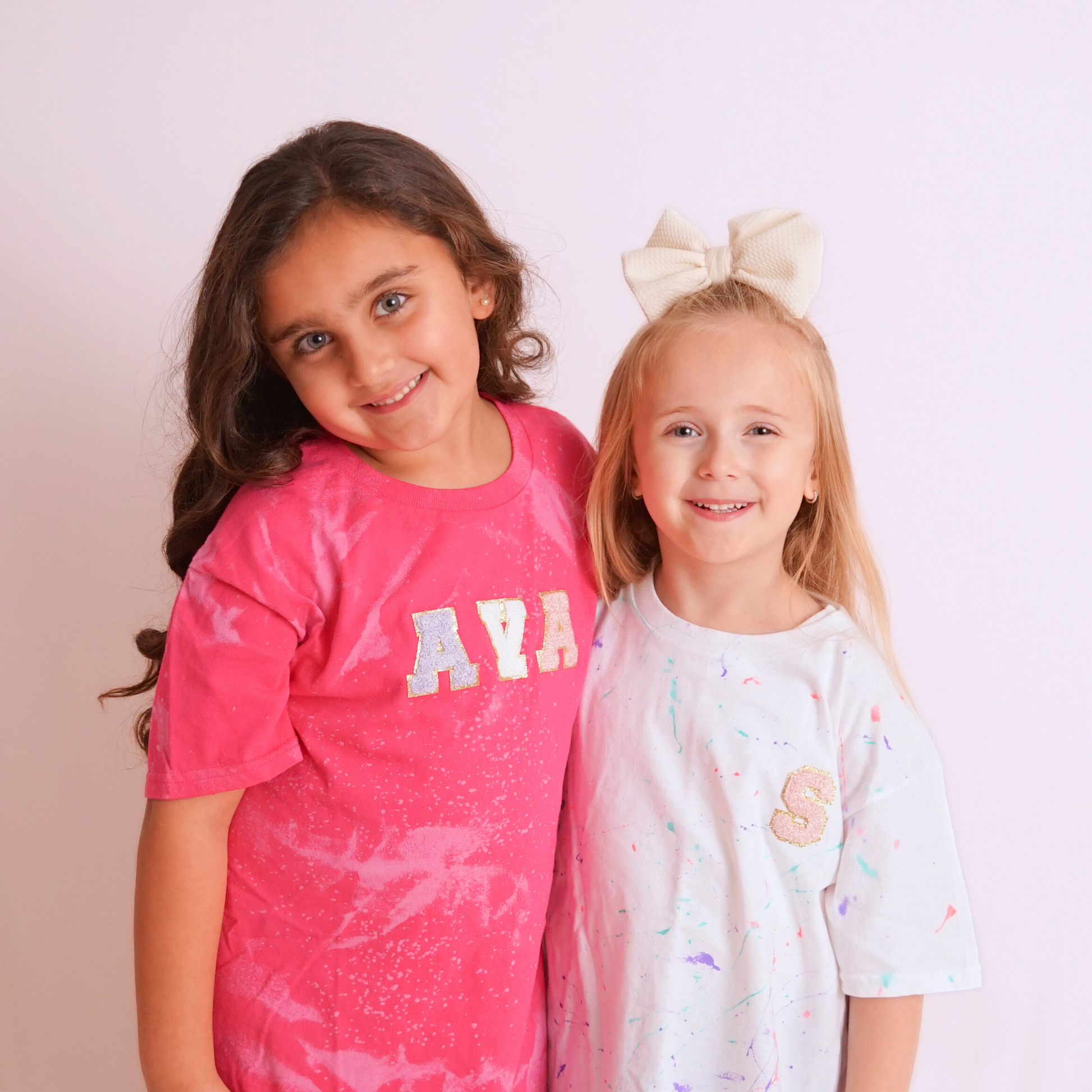 Two young girls posing together against a plain background