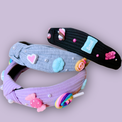 Close-up of three charm headbands—black, gray and purple—laid out on a lavender background