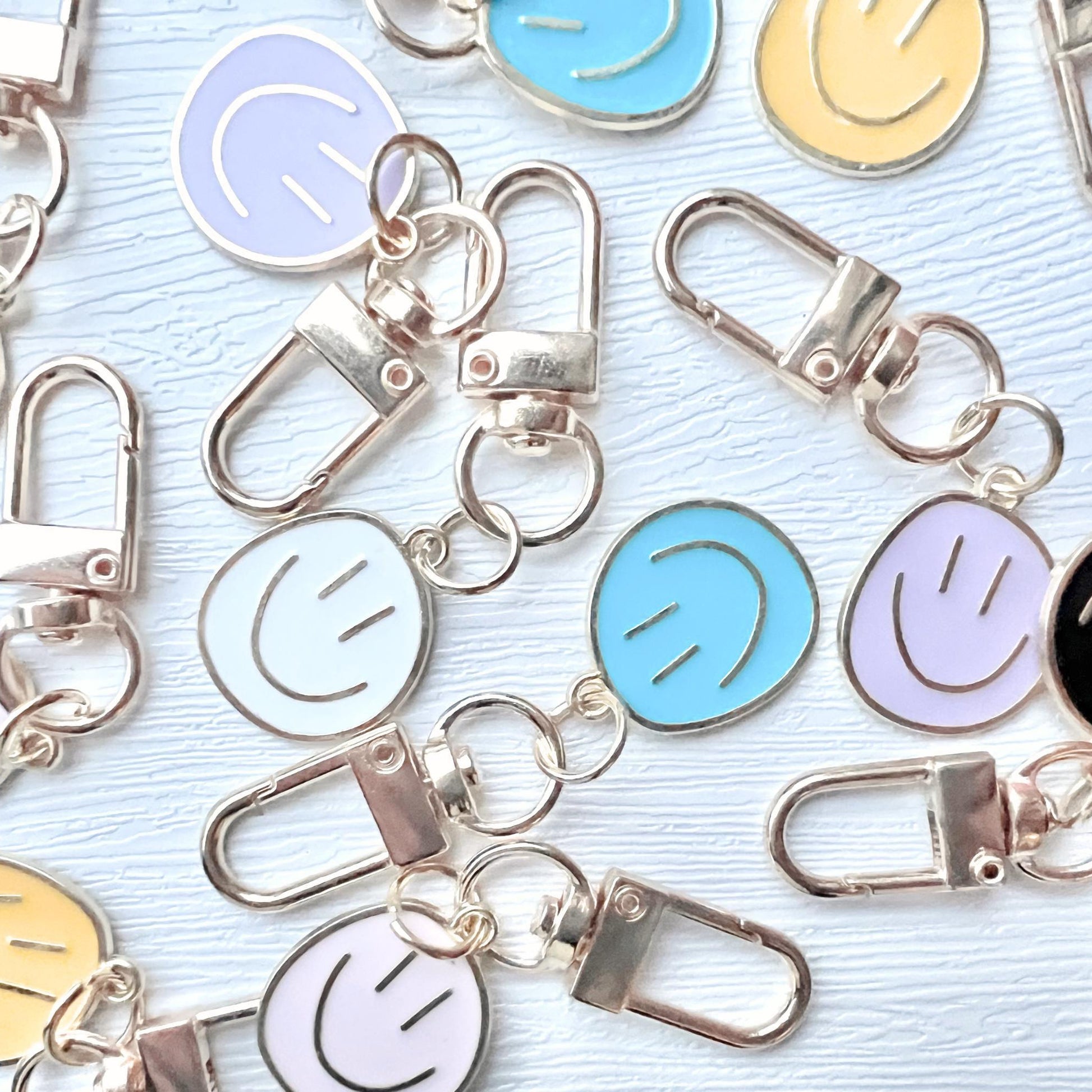 Colorful smiley face keychains with metal clasps on a light blue background