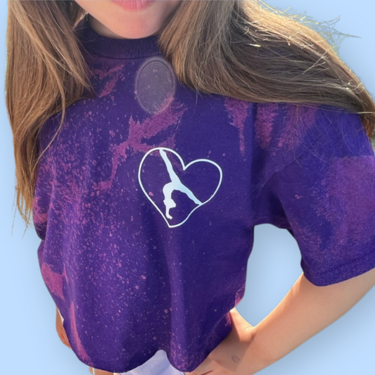 Person wearing a purple t-shirt with a white heart design on a light blue background