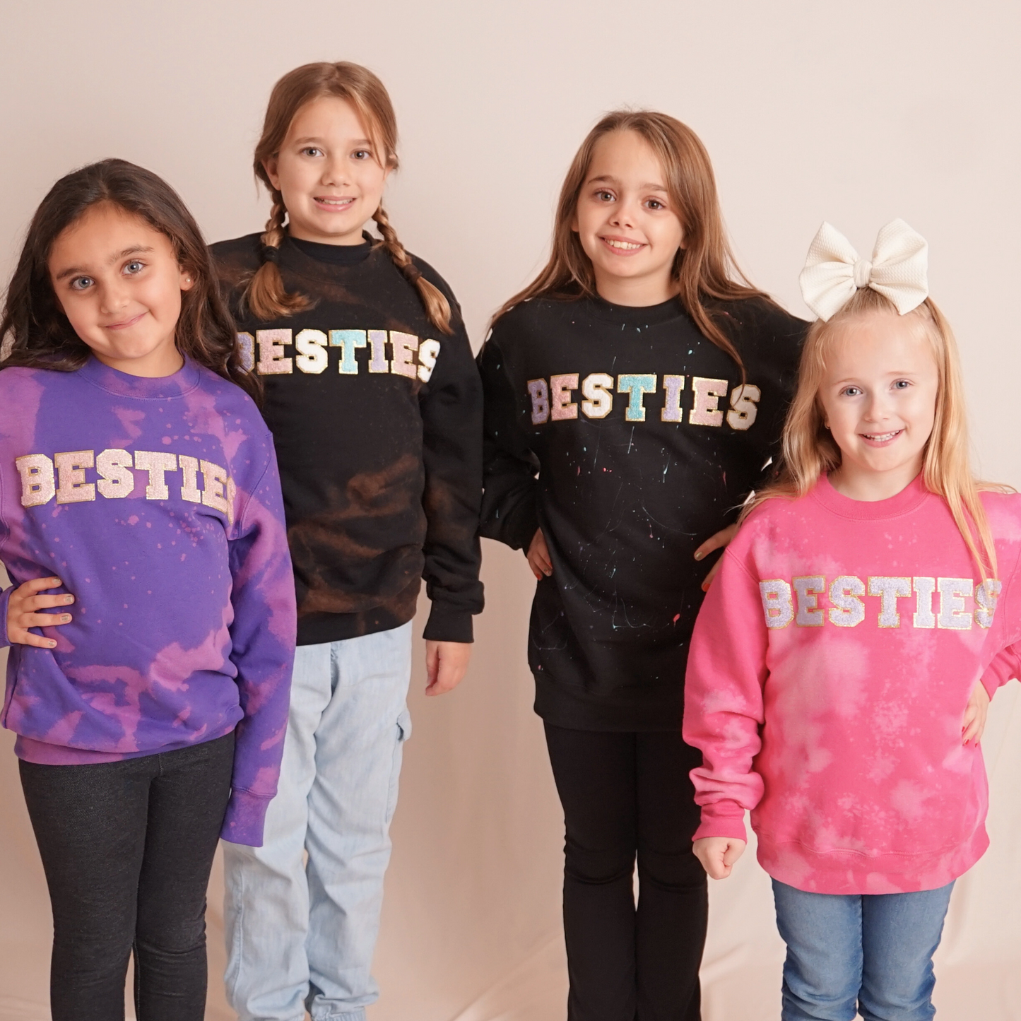 Four children wearing 'BESTIES' sweatshirts in various colors on a plain background
