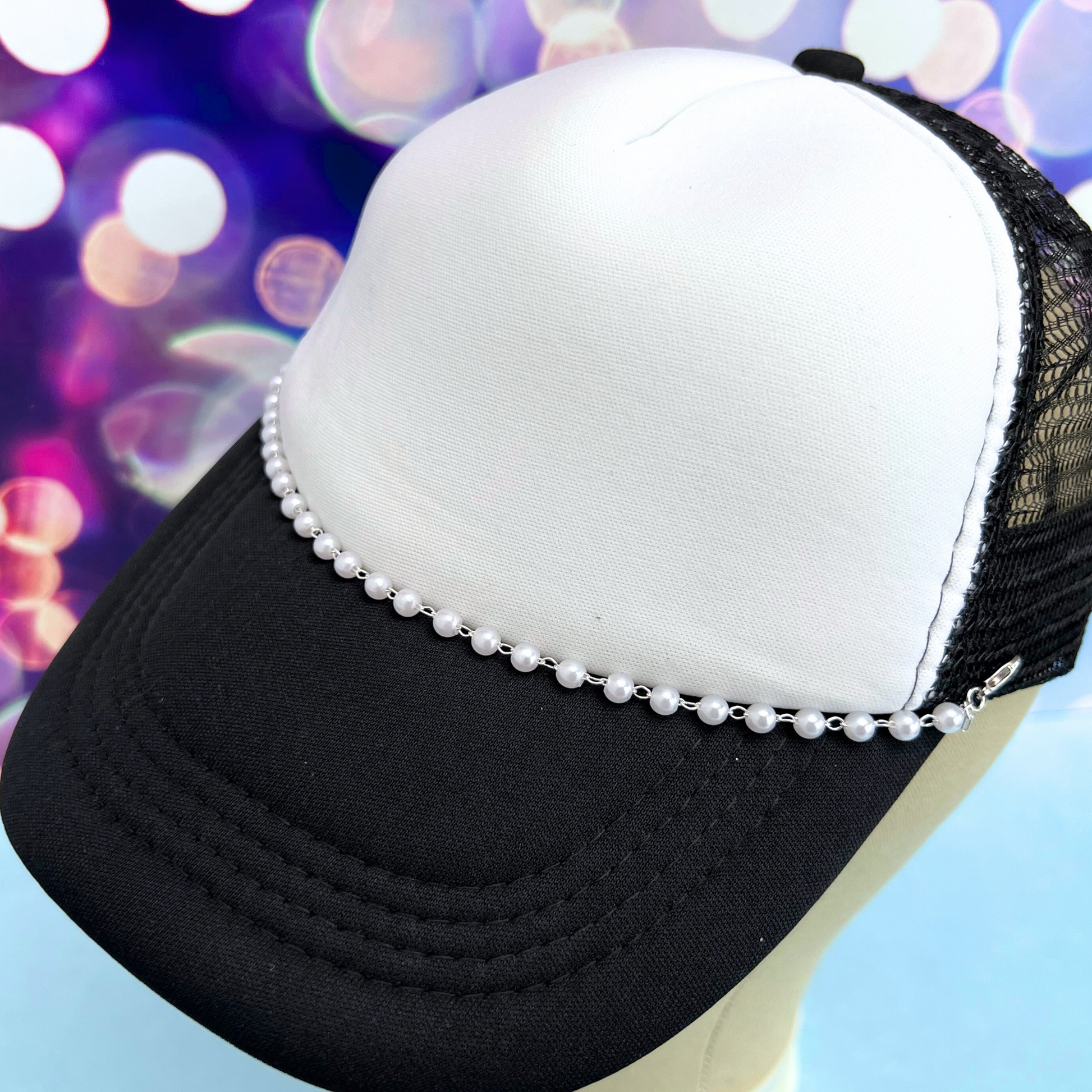 Black and white cap with pearl embellishments on a colorful blurred background