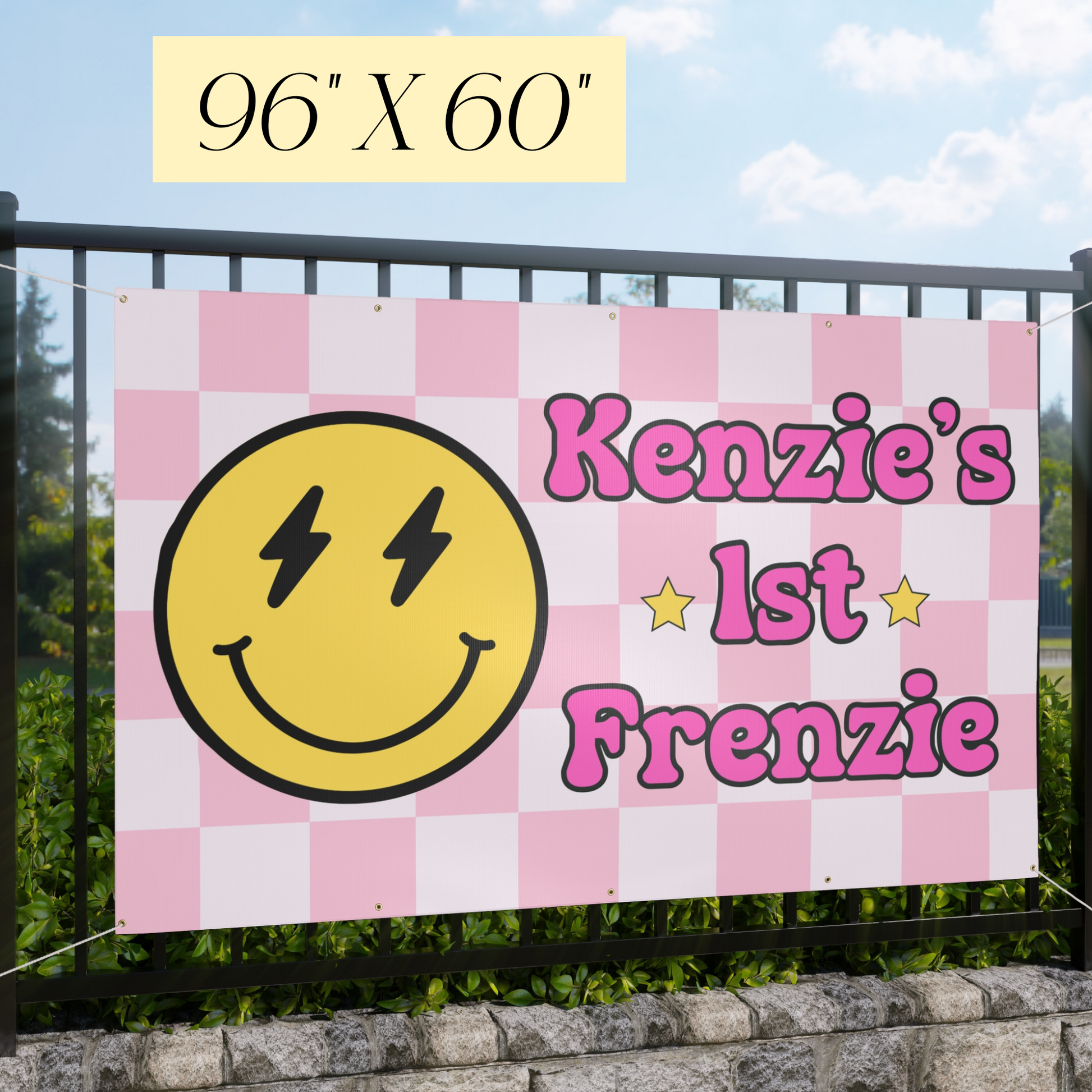 Checkered banner with smiley face and text 'Kenzie's 1st Frenzie' against a fence and sky background