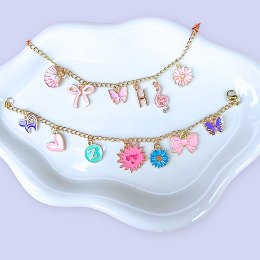 Gold bracelets with colorful charms on a white dish