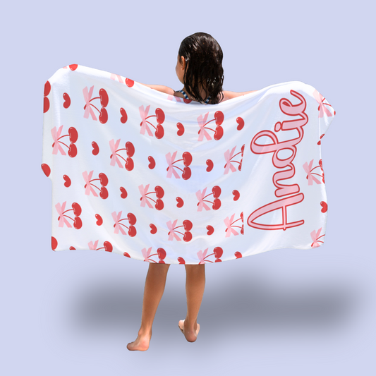 Person wearing a towel with cherry pattern and 'Andie' branding on a light blue background