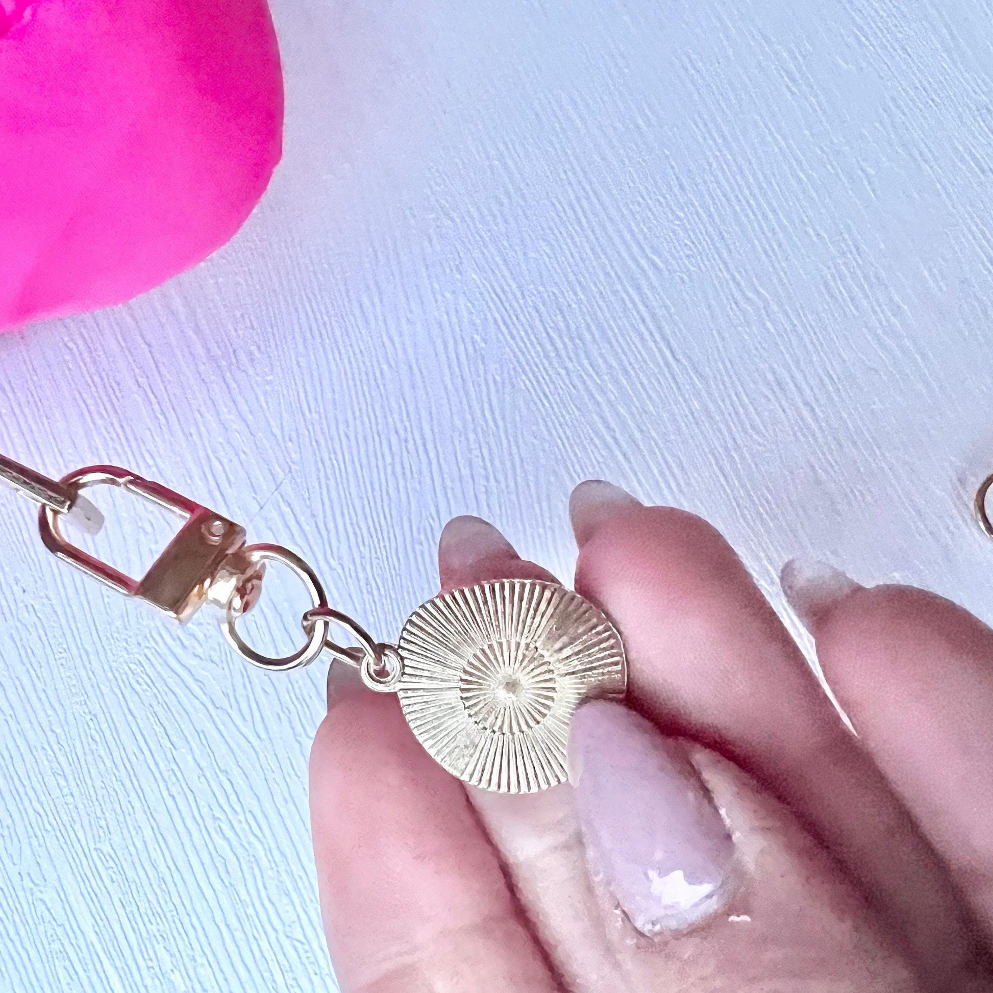 Gold keychain with decorative element held by a hand on a white background