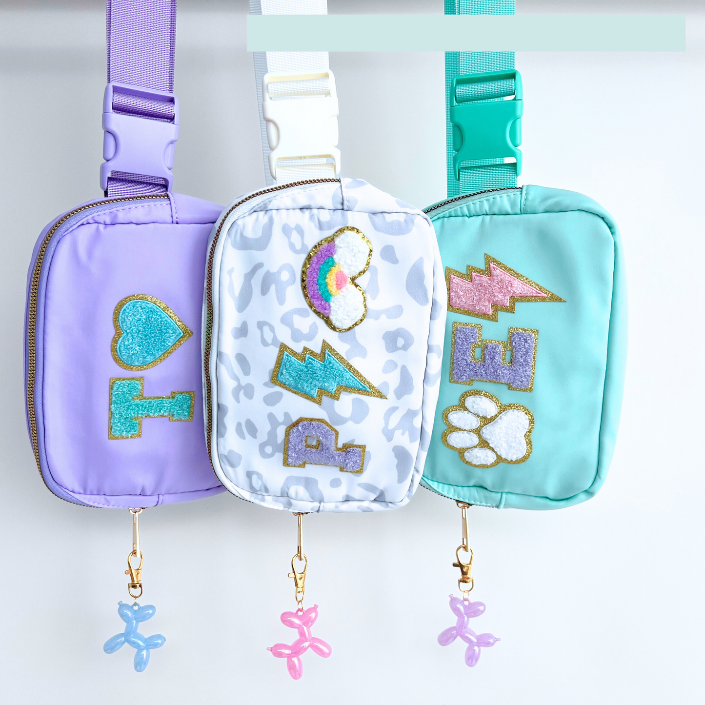 Fanny packs with charm add-ons displayed hanging