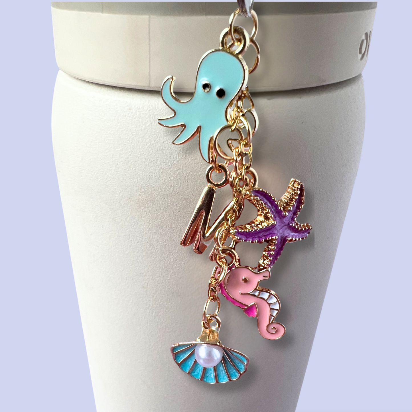 Keychain with ocean-themed charms on a white stand against a light purple background