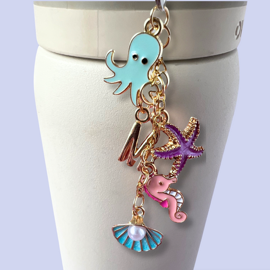 Keychain with ocean-themed charms on a white stand against a light purple background