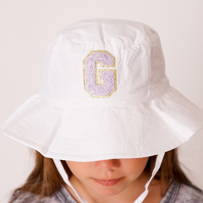 Close-up of white bucket hat with colorful letter patch on front