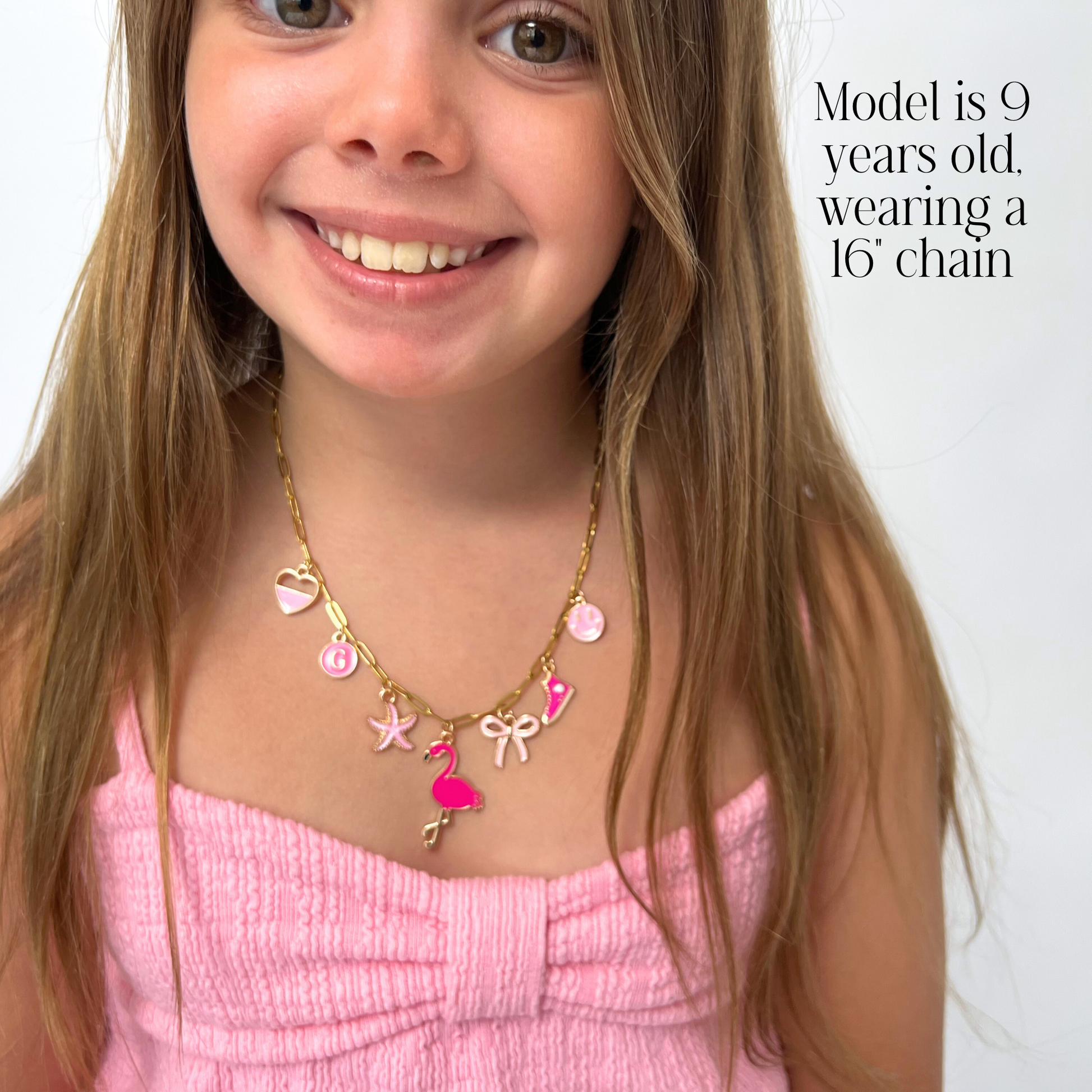 Young girl wearing a gold necklace with pink flamingo charm on a white background